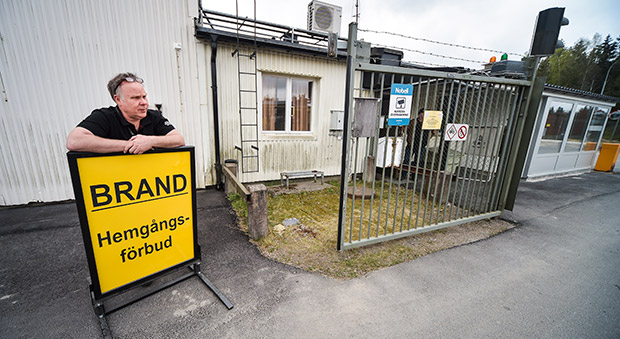 Brandskyddsledaren Johan Lidgren står bakom en gul skylt med texten hemgångsförbud.