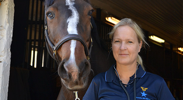 Kristin af Malmborg, klädd i blå t-shirt, bredvid sin häst.