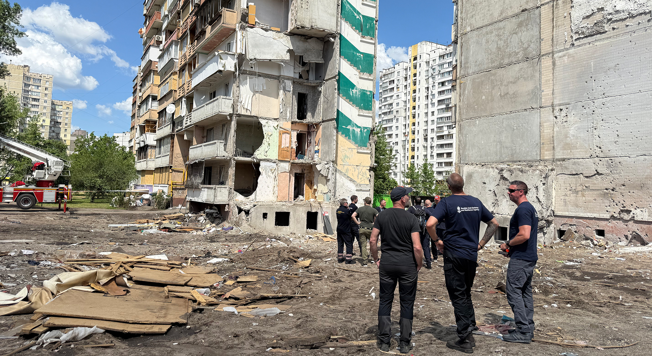 Brandmän framför bombat hus