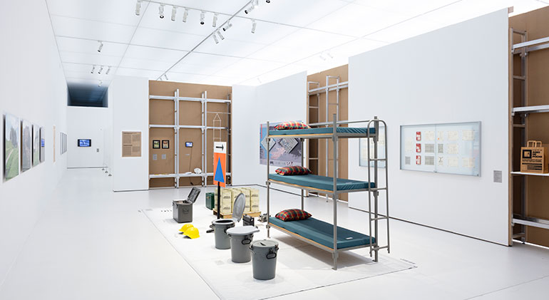 Ett rum på utställningen som bland annat visar en trippel-våningssäng och olika kärl.