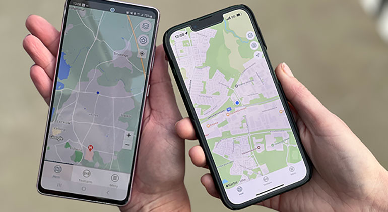 Två händer håller mobiltelefoner med kartor i.