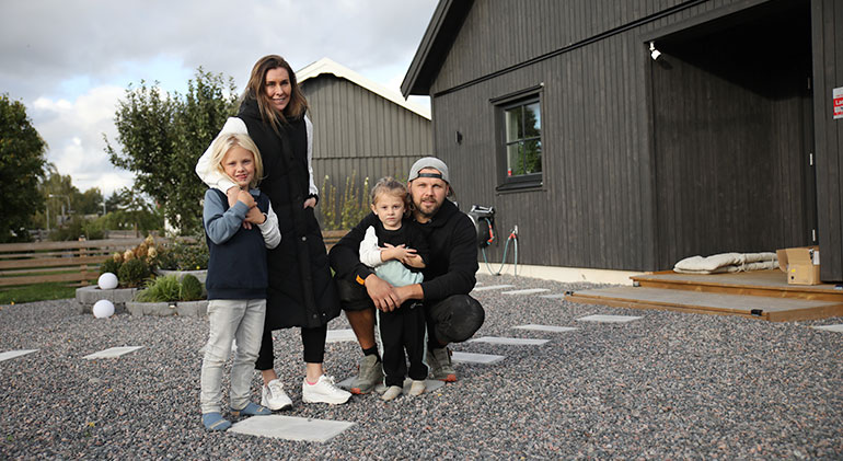 Stephanie Pizzignacco och Nisse Eriksson med sina två barn framför familjens hus.