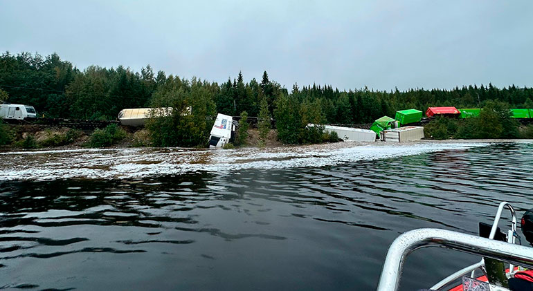 Tåg som spårat ut och några vagnar har delvis vält ner i en sjö.