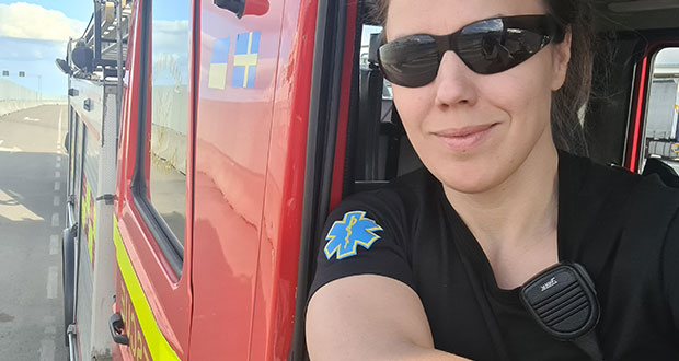 Närbild på Lena Wilderäng klädd i solglasögon och t-shirt från räddningstjänstförbundet, när hon sitter på förarplatsen i en brandbil med nervevat fönster.