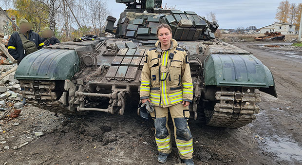 Lena Wilderäng klädd i larmställ framför en övergiven, rysk stridsvagn.