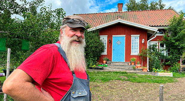 Patrick Sellman framför sitt röda hus med blå dörr.