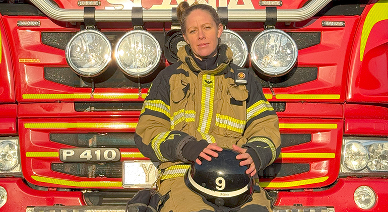 Kvinnlig brandman framför en brandbil