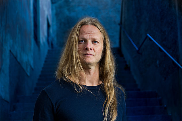 Porträtt på zombieöverlevnadsexperten Herman Geijer. Han står framför en trappa i en mörk gränd.